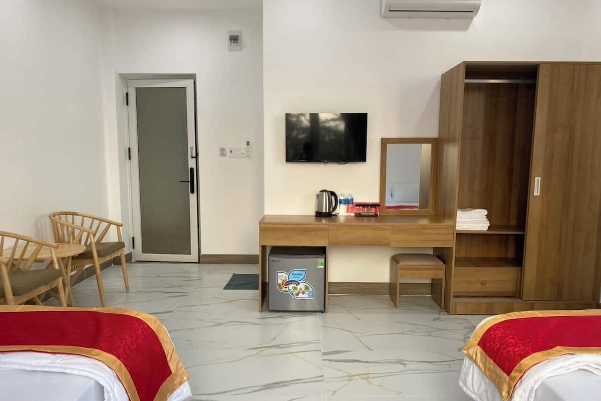 Une chambre d’hôtel avec deux lits, un bureau, une télévision, une armoire et un réfrigérateur.