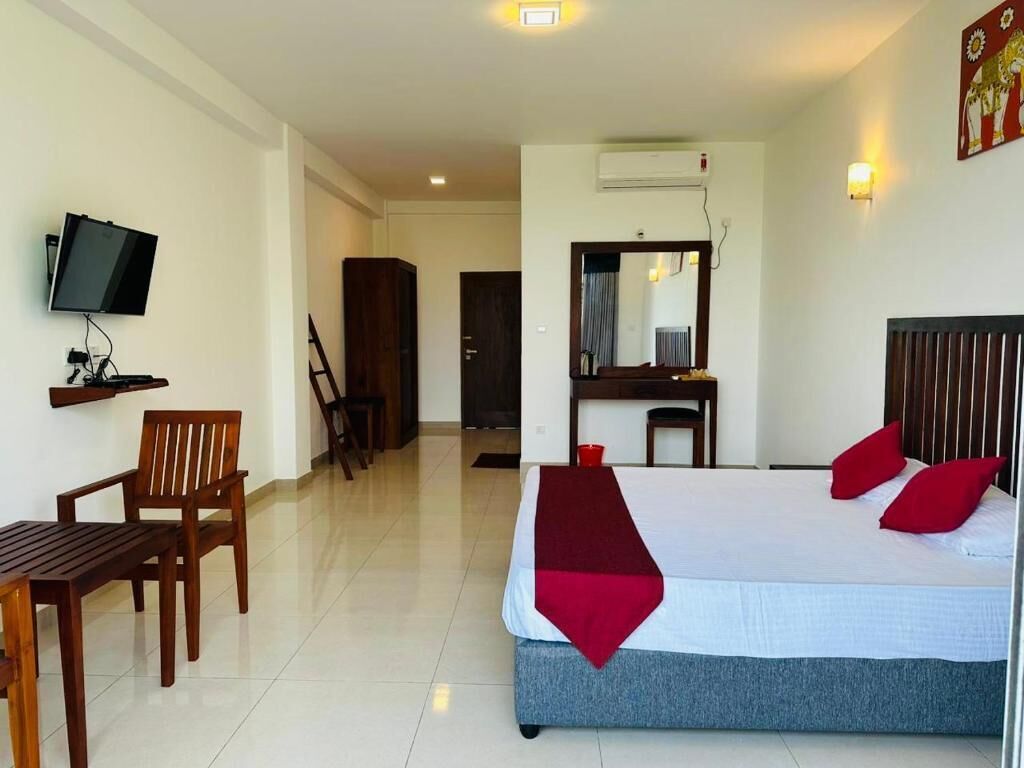 A hotel room with a bed, a desk, a chair, a television, and a mirror.