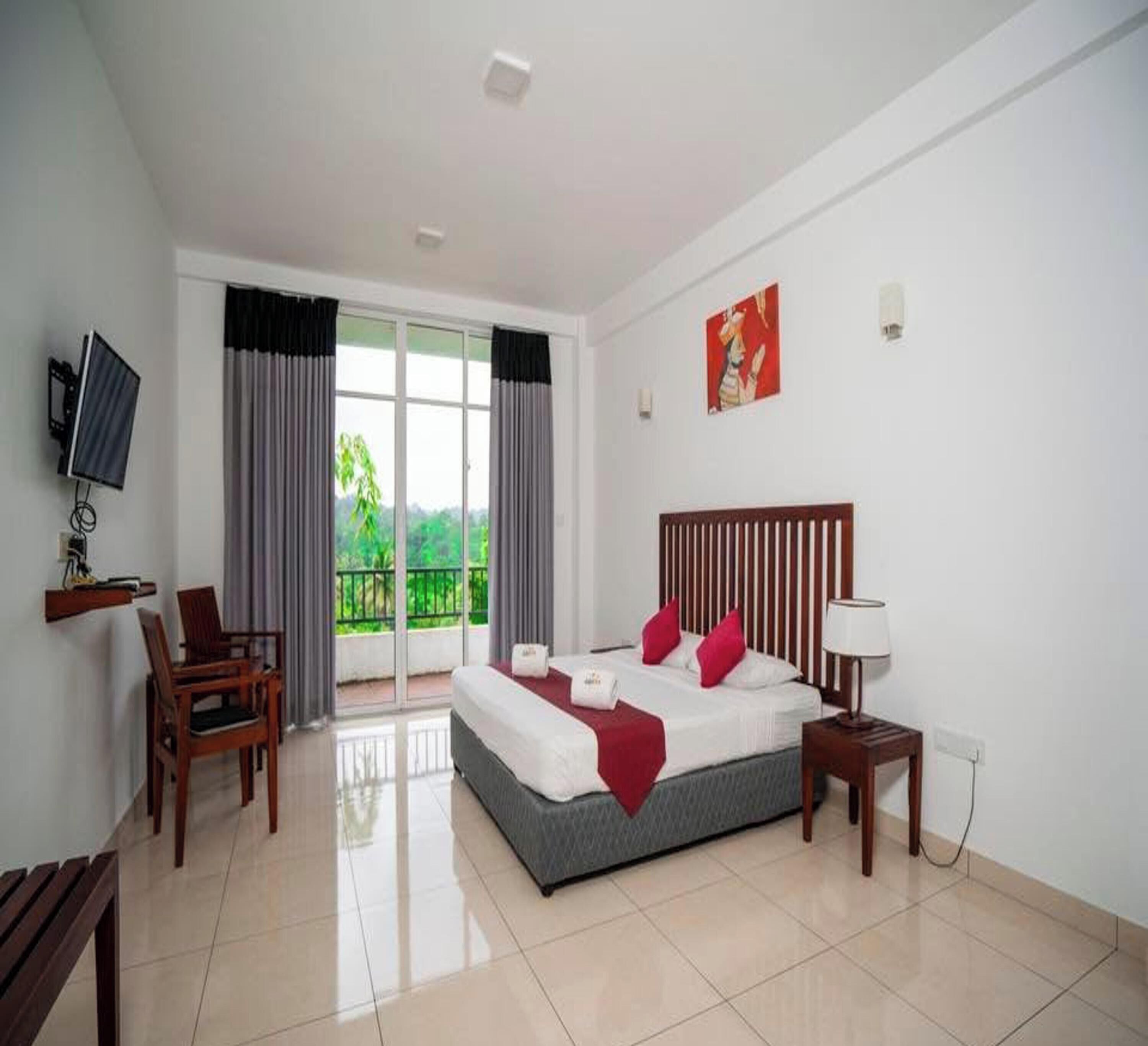 A hotel room with a bed, a TV, a desk, and a chair.