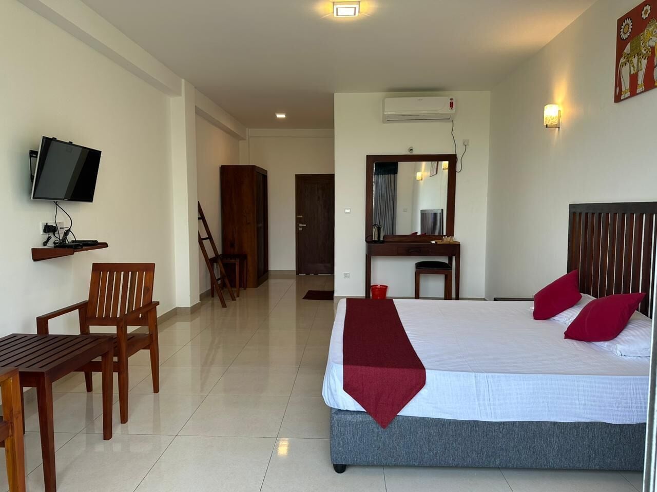 A hotel room with a bed, a desk, a chair, a television, and a mirror.
