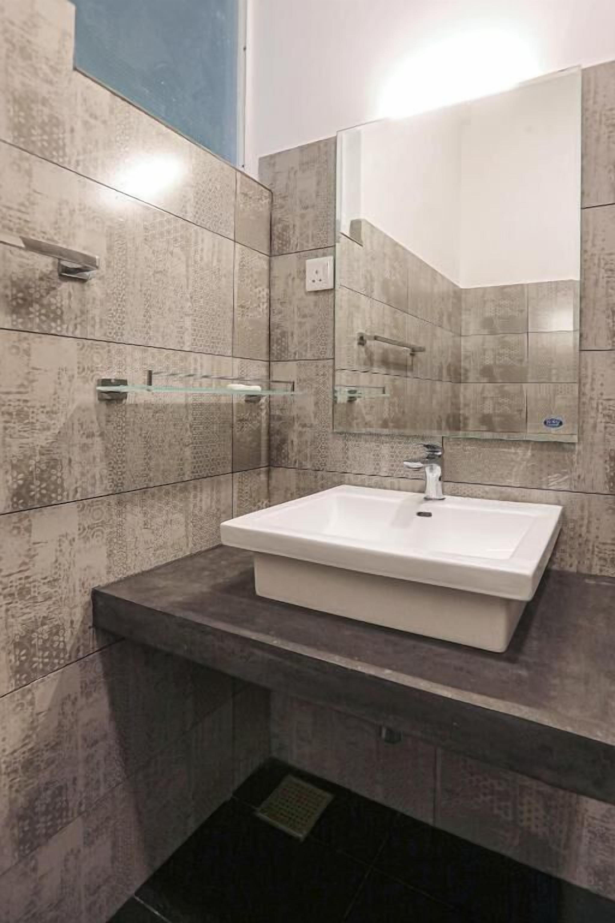 A bathroom with a rectangular sink, a mirror, and tiled walls.