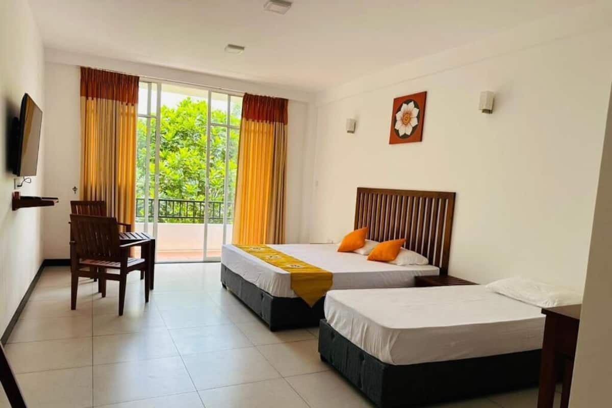A hotel room with two beds, a desk, and a TV.