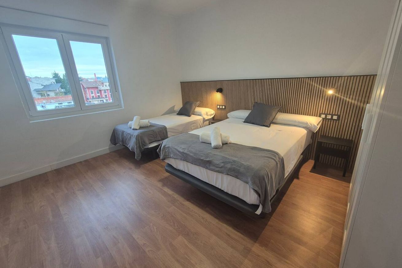 A hotel room with two beds, a large window, and a city view.