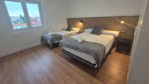 Ein Hotelzimmer mit zwei Betten, einem großen Fenster und Blick auf die Stadt.