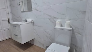 Ein Badezimmer mit Waschbecken, Spiegel, Toilette und Marmorfliesen.