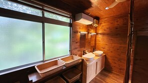Baño de cabaña de madera con dos lavamanos, ventana y espejo.