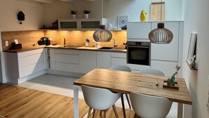 Una cocina moderna con encimera de madera, armarios blancos y luces colgantes.