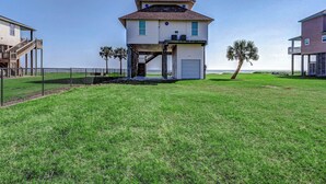 A beachfront house with a balcony, a staircase leading to the main floor, and a view of the ocean.