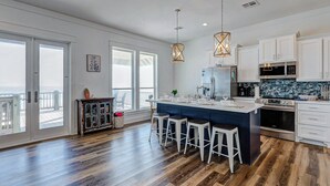 A spacious kitchen with a large island, white cabinetry, and modern appliances.