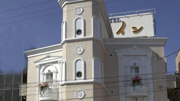 Um edifício com uma torre de relógio, uma varanda florida e uma placa com um símbolo.