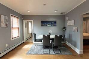 A dining area with a table, chairs, and a painting of a bridge.