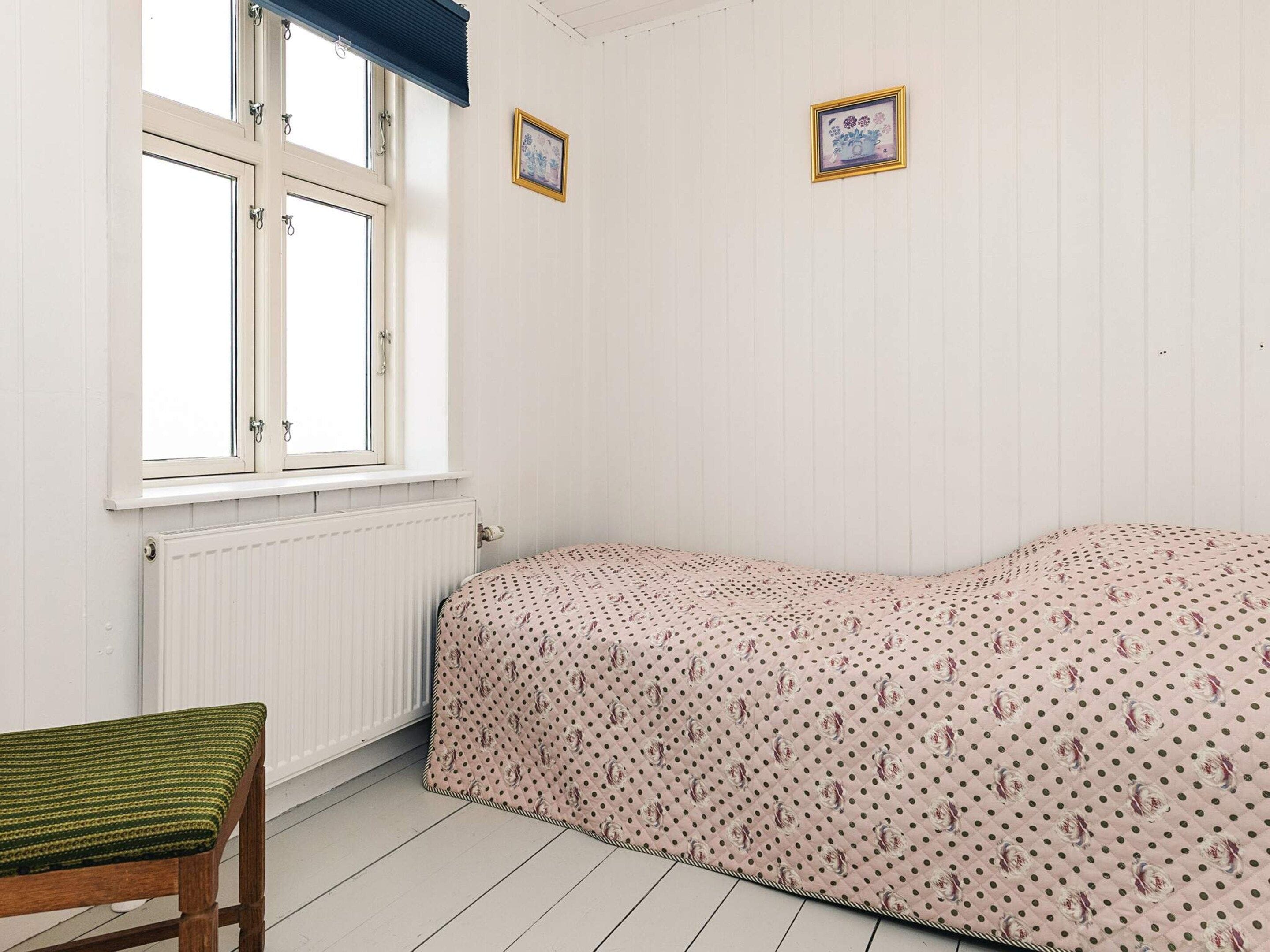 Et værelse med en enkelt seng, et vindue, en radiator og en stol.