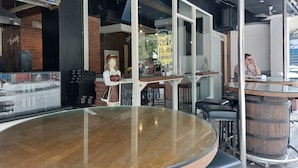 A restaurant with a glass enclosure, a mannequin, and a wooden barrel.
