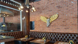 A restaurant interior with brick walls, leather booths, and tables with menus.