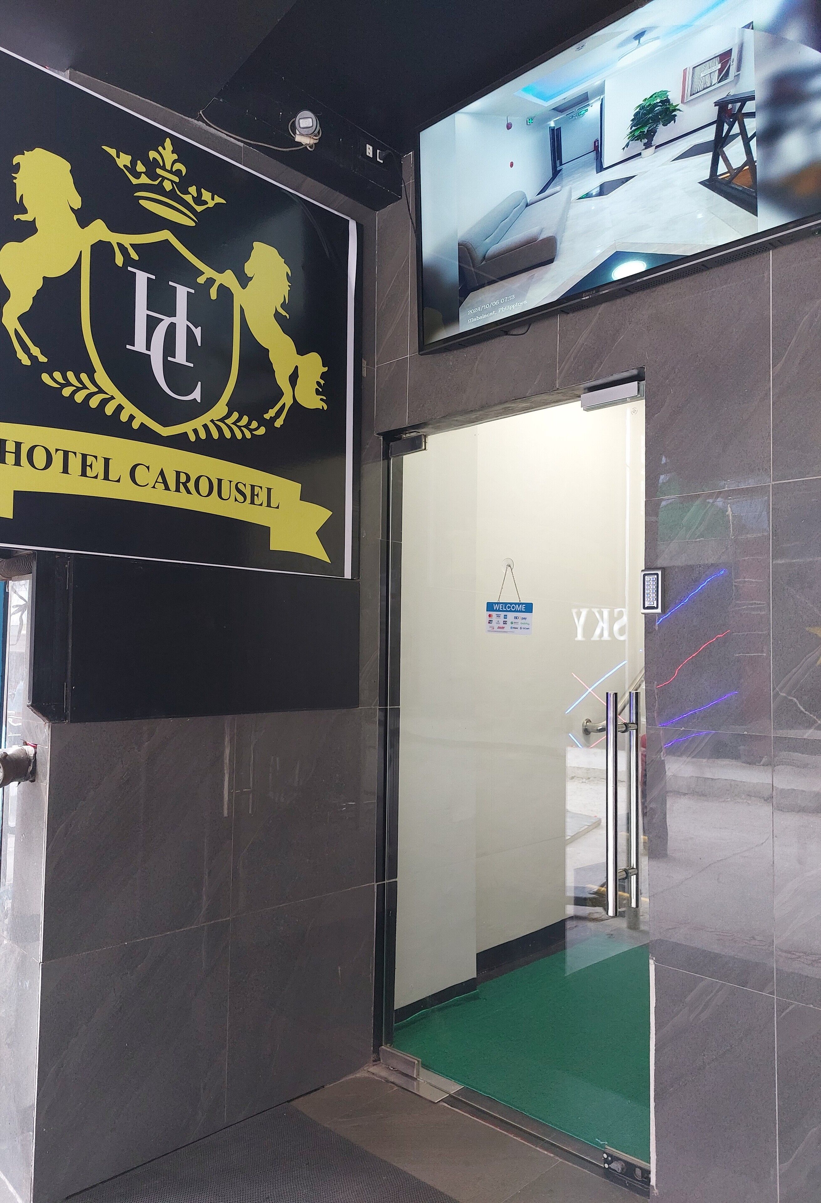 A hotel entrance with a black sign displaying a crest and the name "HOTEL CAROUSEL".
