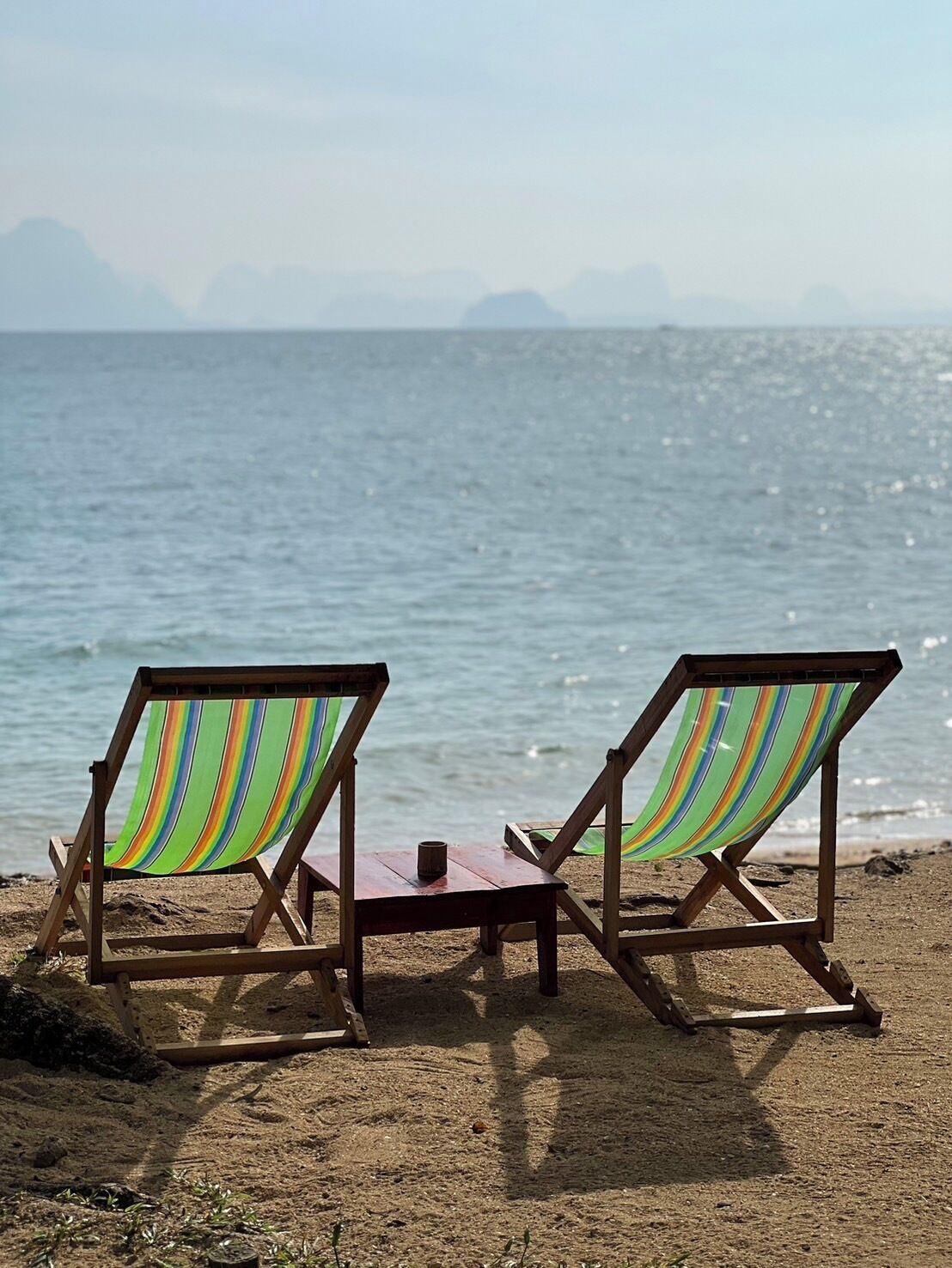 Two beach chairs with striped fabric facing the ocean.