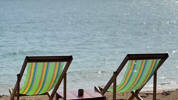 Two beach chairs with striped fabric facing the ocean.