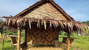 A thatched-roof hut with a wooden floor and benches. - Three ladies (Ko Yao)