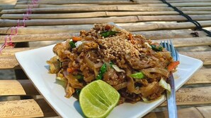A meal on a wooden table with a view of a beach and ocean in the background. - Three ladies (Ko Yao)