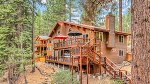Une cabane en bois à plusieurs étages, dotée de terrasses extérieures et d’un patio couvert.