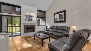 Una sala de estar moderna con chimenea, sofás de cuero y ventanas amplias con vistas al exterior.