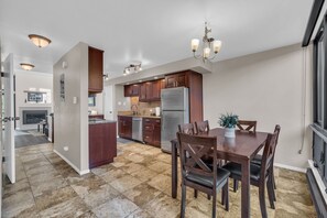 A modern kitchen with dark wood cabinets, stainless steel appliances, and a dining area with a wooden table and chairs. - Park City Golf Course Condo: Pool & Hot Tub Access (Park City)