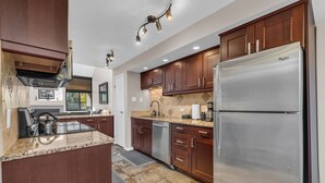 Una cocina moderna con armarios de madera oscura, electrodomésticos de acero inoxidable y encimeras de granito.