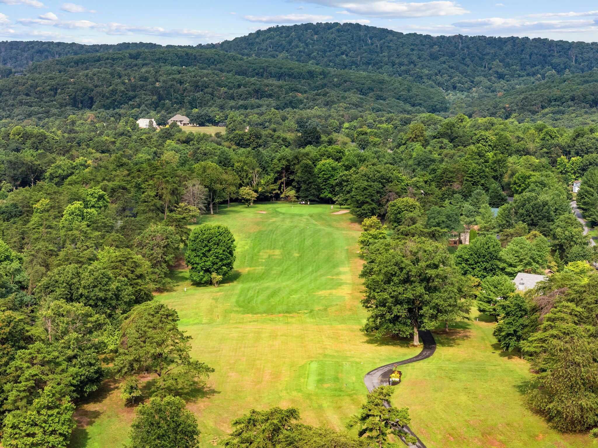 Un parcours de golf entouré d’une forêt dense et de collines.