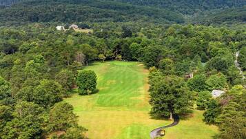 Un parcours de golf entouré d’une forêt dense et de collines.