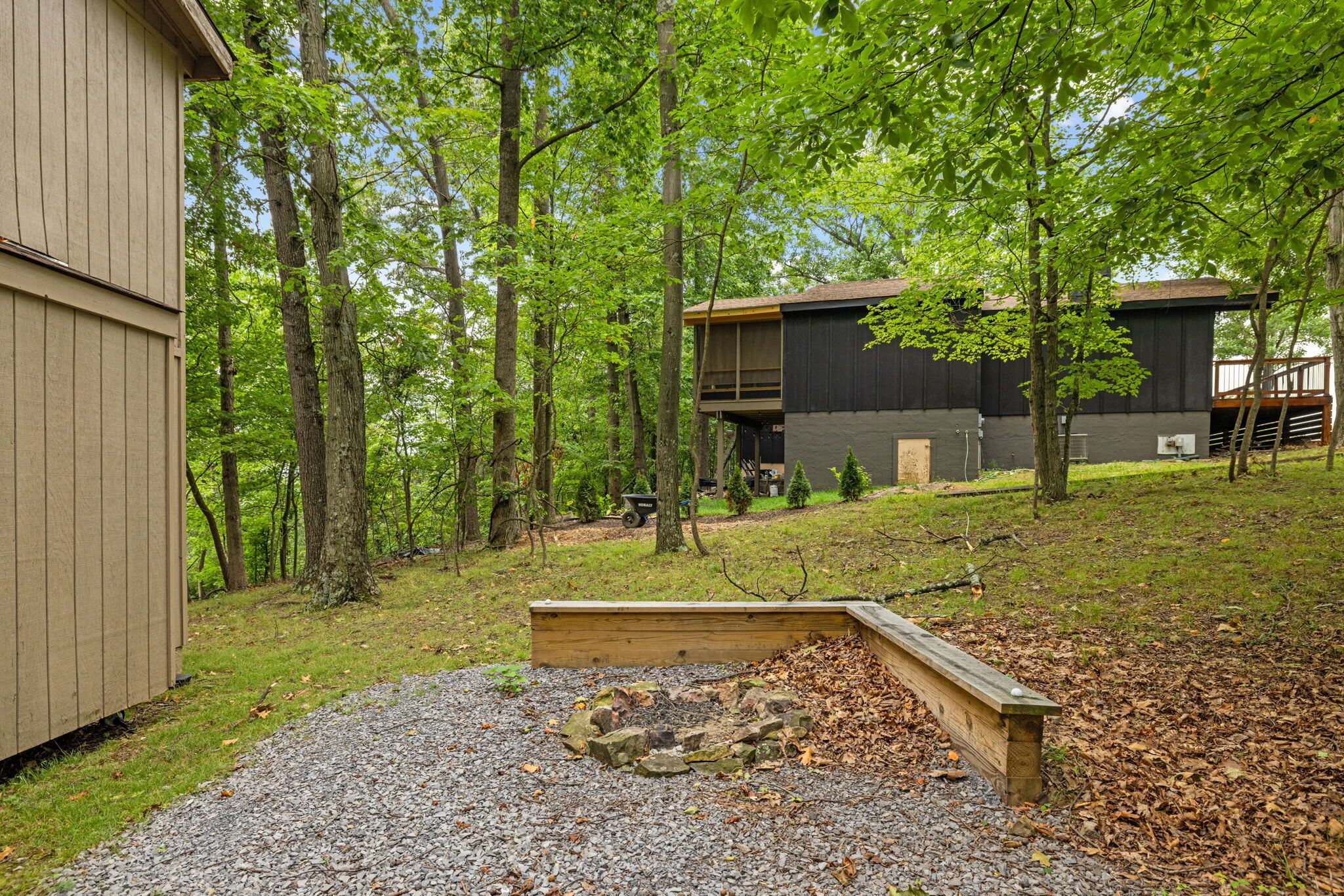 A residential area with a wooden deck, a gravel area with rocks, and a building with a dark facade.