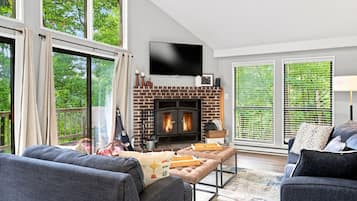 Een moderne woonkamer met een open haard, grote ramen en comfortabele zithoek.