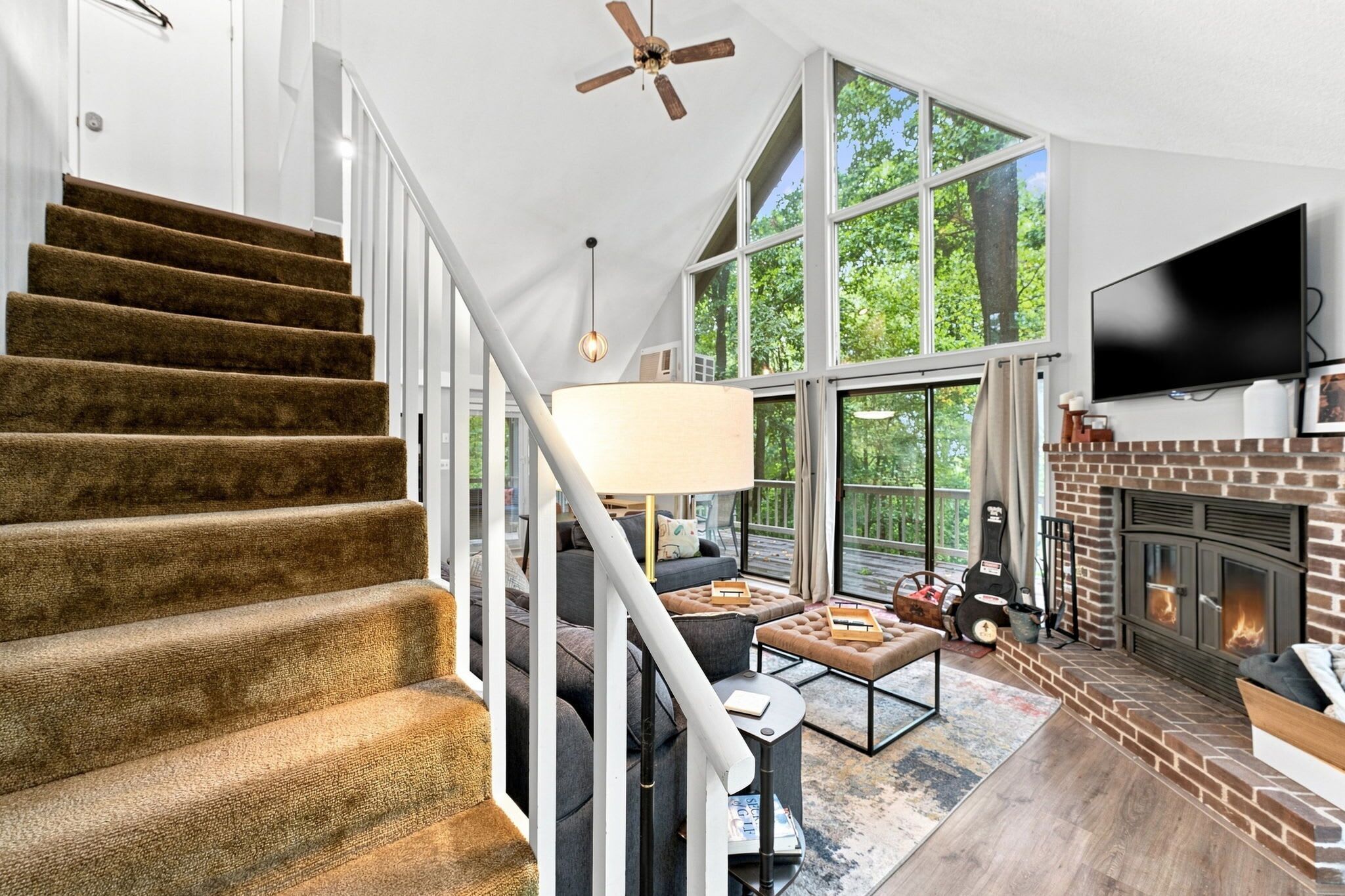 A spacious living area with a fireplace, a large window, and a staircase.