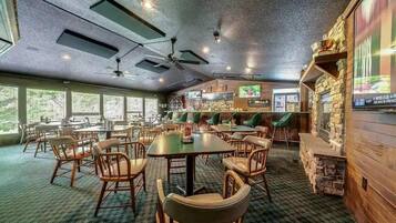 Un restaurant doté de nombreuses tables et chaises, d’un bar et d’un écran de télévision.