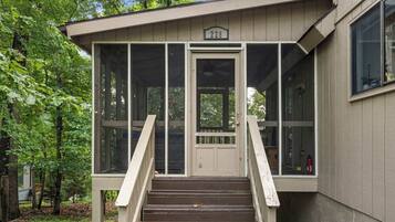 A wooden structure with a number '228' above the door, a set of stairs leading up to it, and a glass enclosure on the upper level.