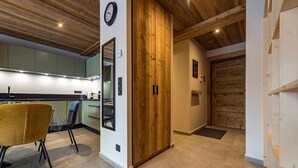 A modern kitchen with wooden ceiling beams, a dining area with a yellow chair, and a wooden door. - New apartment in resort center - sleeps 8/9 (ST SORLIN D ARVES)