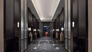 Un couloir moderne doté d’un plancher poli, d’un éclairage encastré et d’une porte centrale donnant accès à un autre espace.