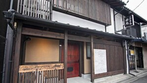 A traditional Japanese building with a wooden entrance, a red door, and a signboard. - Onju Kamikyo (Kyoto)