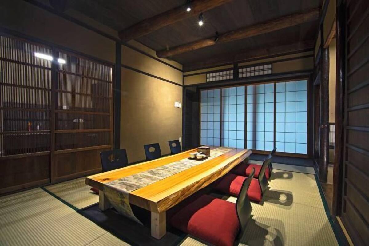 A traditional Japanese-style room with tatami flooring, a low table, and red cushions.