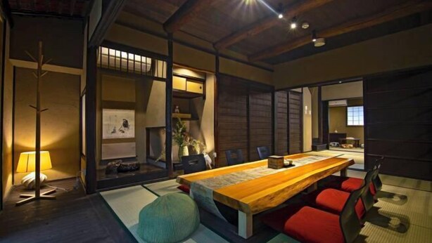A traditional Japanese-style room with tatami flooring, a low wooden table, red cushions, and a sliding door. - Onju Kamikyo (Kyoto)