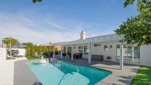 Una casa moderna con piscina, patio cubierto y jardín.