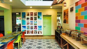 A dining area with a long table, colorful chairs, and a patterned floor. - Daksh Elite Candolim Goa (Candolim)