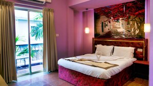 A bedroom with a bed, a painting, and a view of a balcony. - Daksh Elite Candolim Goa (Candolim)