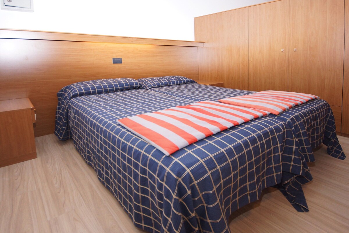 Een slaapkamer met een bed, een houten garderobe en een klein nachtkastje.
