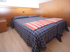 Une chambre à coucher avec un lit, une armoire en bois et une petite table de chevet en bois.