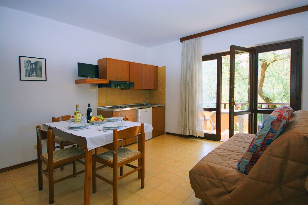 Een compacte leefruimte met een eethoek, kitchenette en een bank met uitzicht.