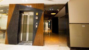 A modern elevator with a wooden panel design, a glass door, and a control panel. - Hotel Anchorage Delhi IGI Airport (New Delhi)