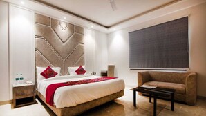 A modern hotel room with a large bed, a sofa, a coffee table, and a large window. - Hotel Anchorage Delhi IGI Airport (New Delhi)