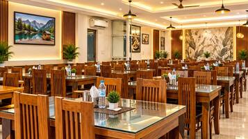 A spacious dining area with multiple tables and chairs, ceiling fans, and pendant lighting.