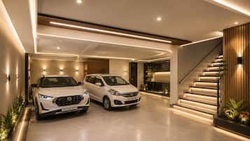 A modern interior with a staircase, two white cars parked in a garage, and a well-lit hallway.