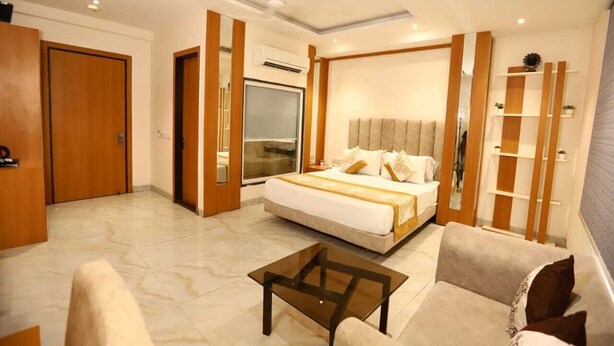 A hotel room with a large bed, a sofa, a coffee table, and a wardrobe. - Hotel Anchorage Delhi IGI Airport (New Delhi)